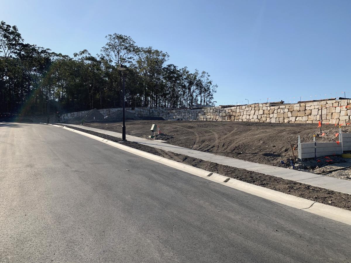 A finished street with footpath, lamp post and sandstone wall at Holmview Estate